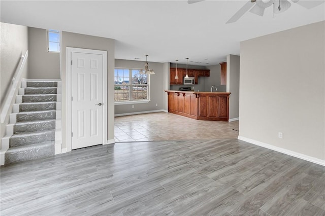 unfurnished living room featuring ceiling fan and light wood-type flooring