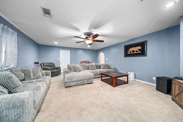 living room featuring ceiling fan, light carpet, and a textured ceiling