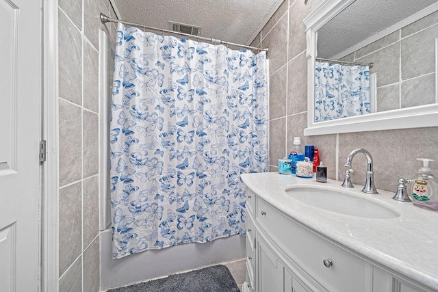 bathroom with shower / bath combination with curtain, vanity, a textured ceiling, and tile walls