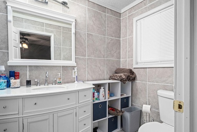 bathroom with tile walls, vanity, toilet, and ceiling fan