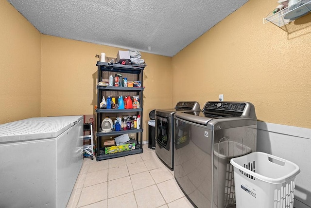 washroom with separate washer and dryer, a textured ceiling, and light tile patterned floors