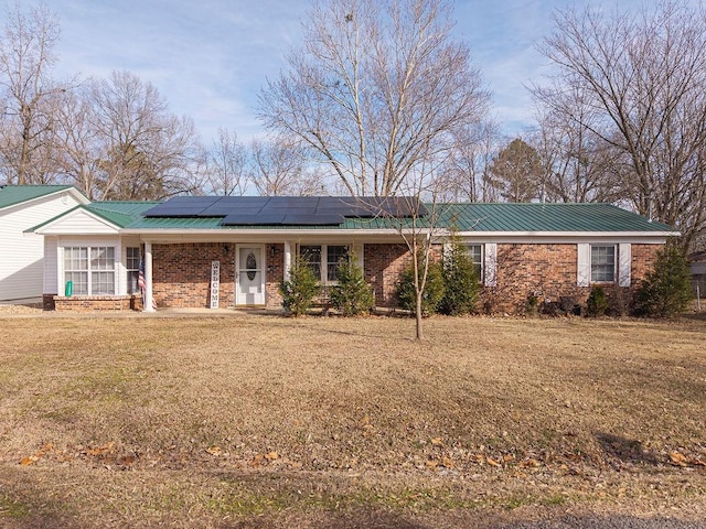 ranch-style home with a front lawn and solar panels