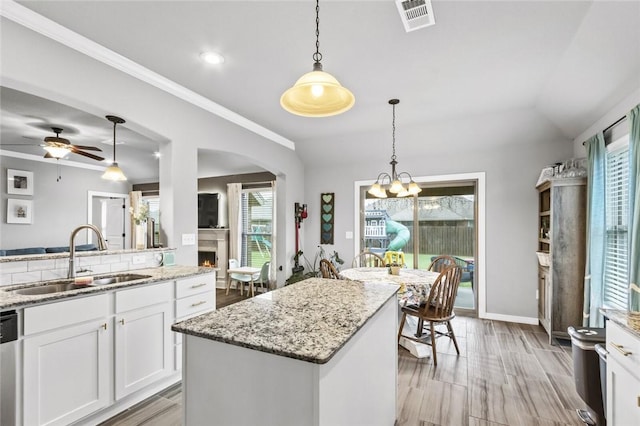 kitchen featuring sink, white cabinets, a kitchen island, decorative light fixtures, and stainless steel dishwasher