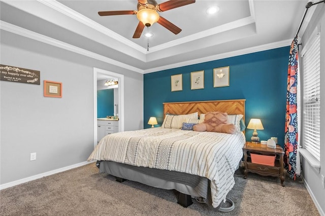 bedroom with ensuite bath, ornamental molding, a raised ceiling, and carpet