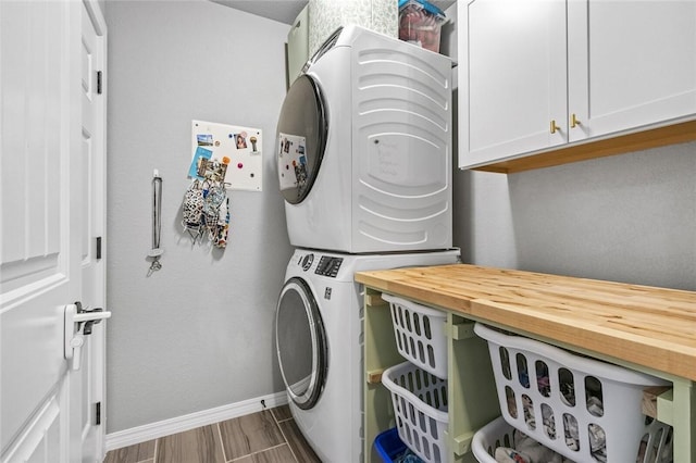 clothes washing area with stacked washer and dryer and cabinets