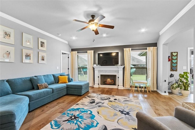 living room with ceiling fan, ornamental molding, a premium fireplace, and light hardwood / wood-style floors