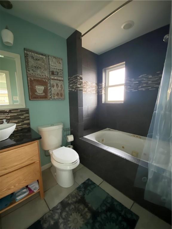 full bathroom with tile patterned floors, toilet, vanity, shower / bath combo, and decorative backsplash