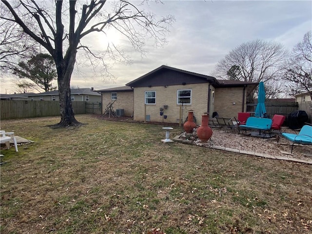 rear view of house with central AC unit and a yard