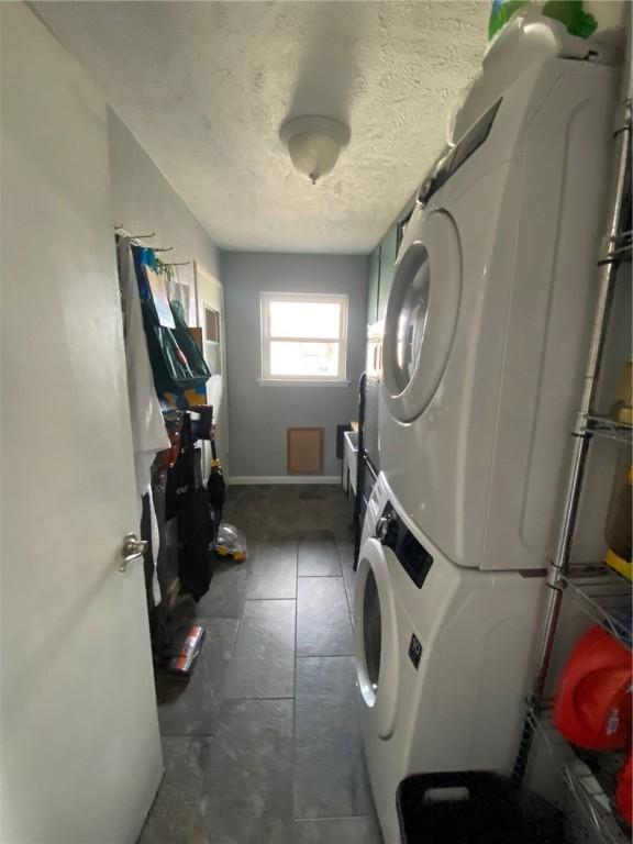 clothes washing area with stacked washer / dryer and a textured ceiling