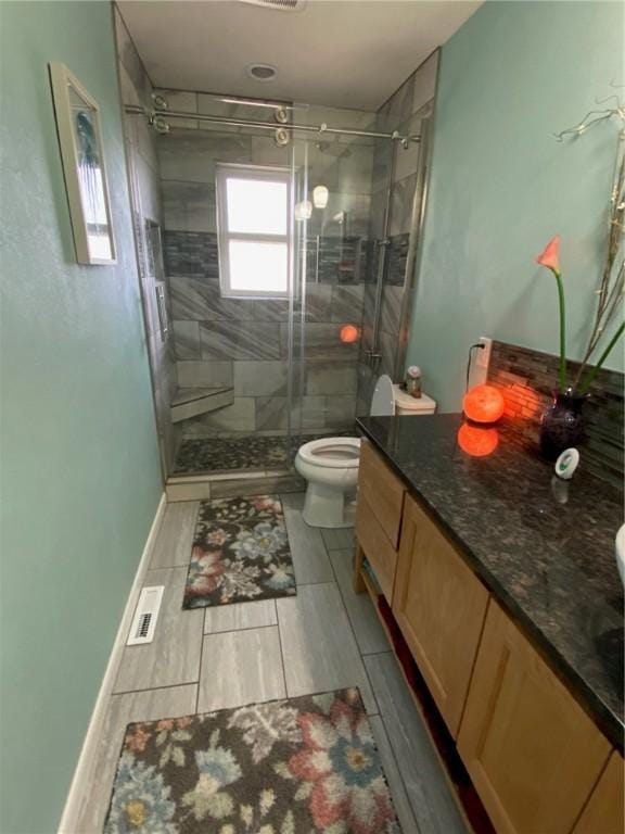 bathroom featuring vanity, toilet, and a shower with door