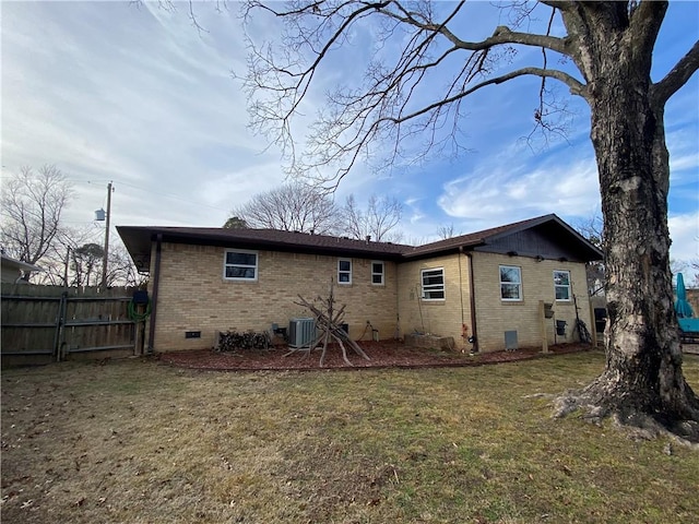 rear view of property with cooling unit and a yard