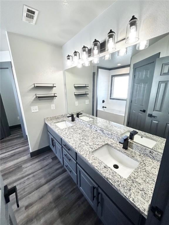 bathroom featuring hardwood / wood-style flooring, vanity, and a tub