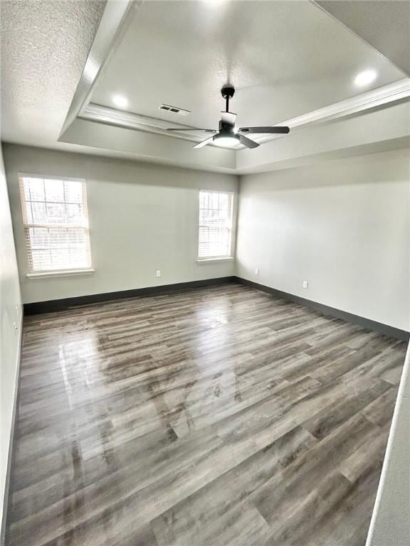 spare room with dark hardwood / wood-style flooring, ceiling fan, a raised ceiling, and a textured ceiling