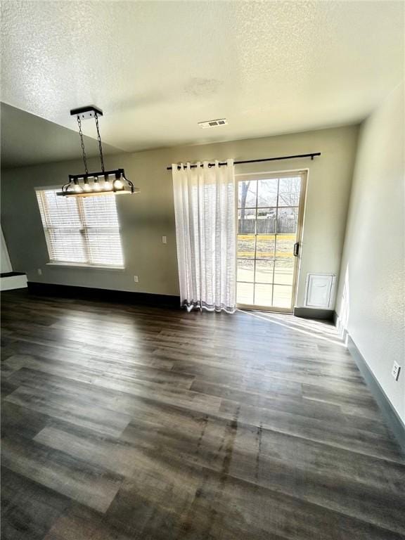 unfurnished dining area with dark wood-type flooring and a textured ceiling