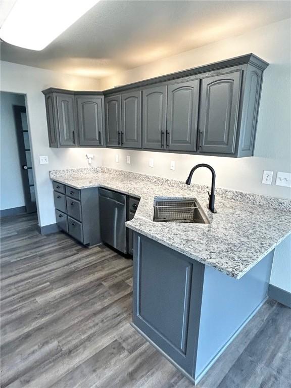 kitchen featuring sink, dark wood-type flooring, stainless steel dishwasher, and kitchen peninsula