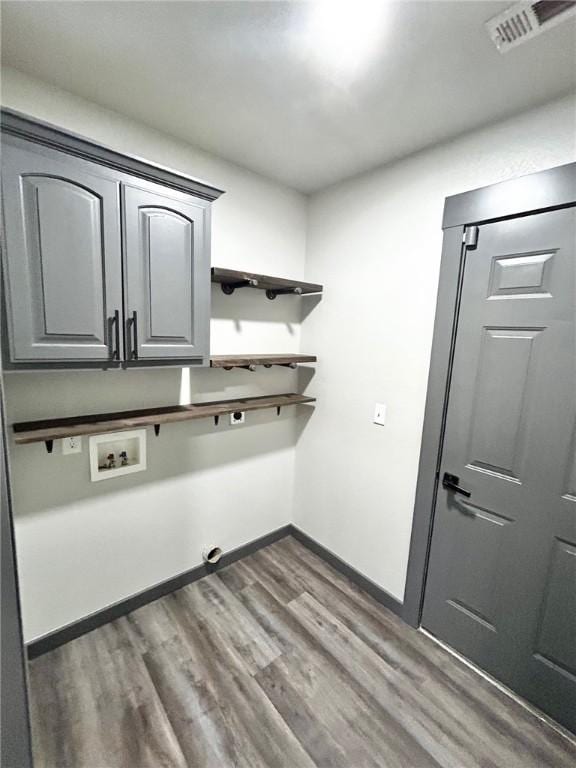 washroom with hookup for a washing machine, dark wood-type flooring, and cabinets