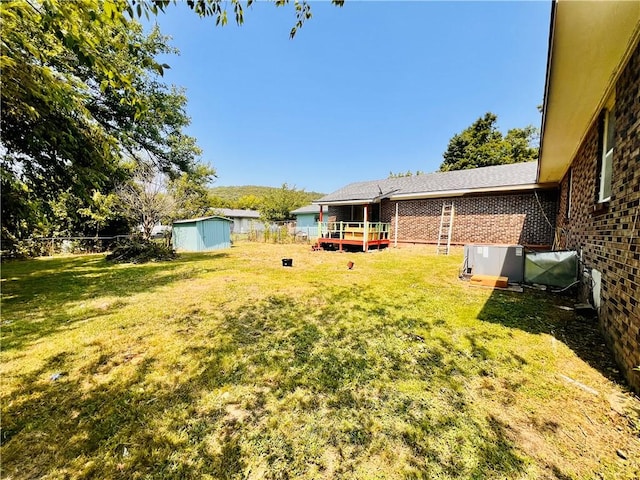 view of yard with a wooden deck, central AC unit, and a shed