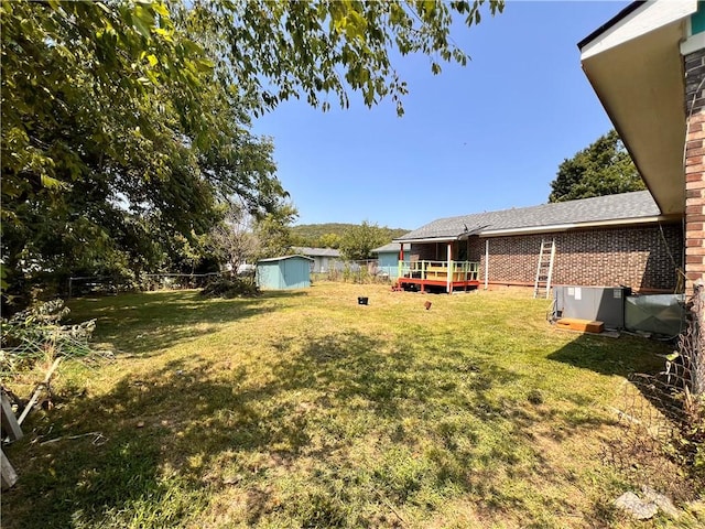 view of yard featuring a wooden deck and a storage unit