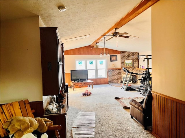 carpeted living room with ceiling fan, wooden walls, a textured ceiling, and vaulted ceiling with beams