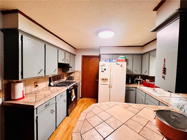 kitchen with light hardwood / wood-style flooring, gray cabinetry, stainless steel appliances, tile counters, and kitchen peninsula