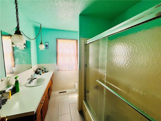 bathroom with vanity, tile walls, tile patterned floors, and a textured ceiling