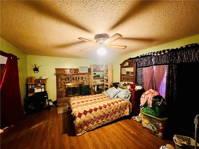 bedroom featuring ceiling fan, dark wood-type flooring, a textured ceiling, and a fireplace