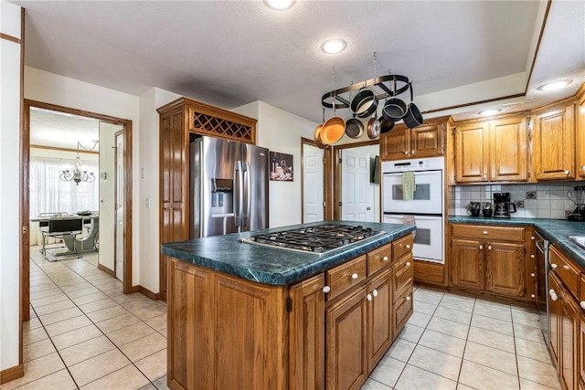 kitchen featuring light tile patterned floors, stainless steel appliances, tasteful backsplash, a kitchen island, and a chandelier