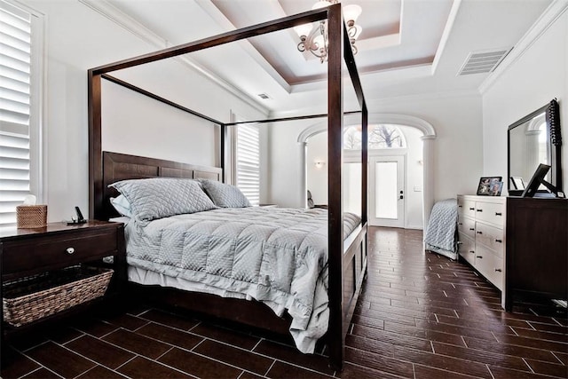 bedroom featuring ornamental molding, an inviting chandelier, and a tray ceiling