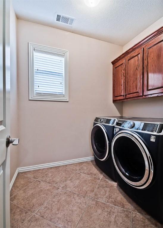 washroom with cabinets, light tile patterned floors, a textured ceiling, and independent washer and dryer