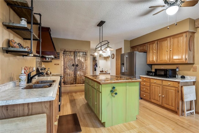 kitchen with sink, green cabinets, high end fridge, a kitchen island, and decorative light fixtures