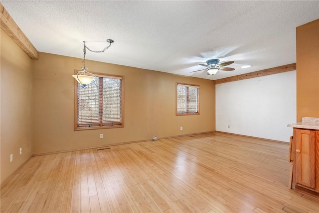 spare room featuring ceiling fan, light hardwood / wood-style floors, and a textured ceiling