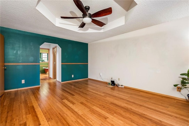 spare room featuring ceiling fan, wood-type flooring, a tray ceiling, and a textured ceiling