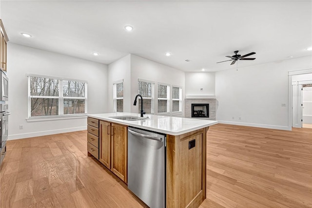 kitchen featuring sink, light hardwood / wood-style flooring, appliances with stainless steel finishes, plenty of natural light, and a kitchen island with sink