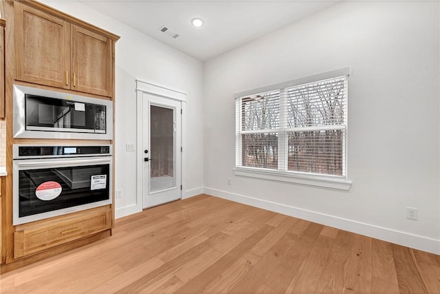 kitchen featuring built in microwave, light hardwood / wood-style flooring, and oven