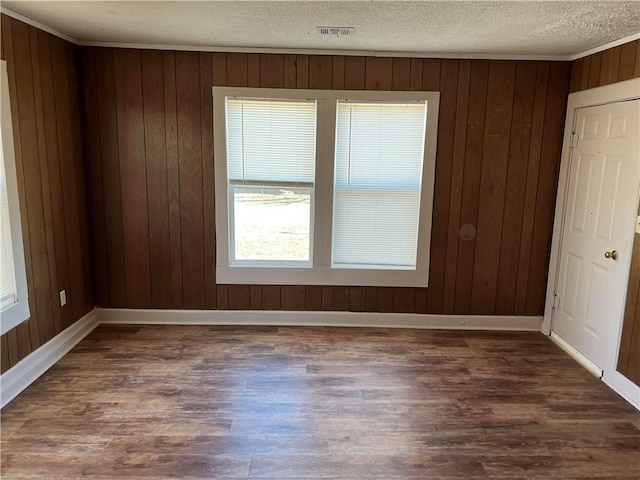 spare room with dark wood-type flooring, a textured ceiling, and wood walls