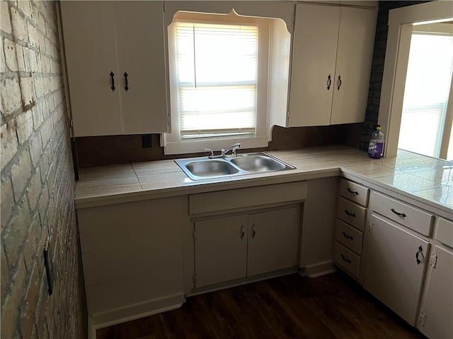 kitchen with dark wood-type flooring, tile countertops, sink, and white cabinets