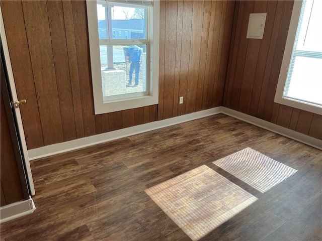 empty room with dark hardwood / wood-style flooring and wood walls