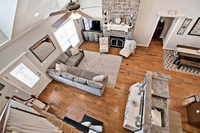 living room featuring ceiling fan, wood-type flooring, a fireplace, and a wealth of natural light