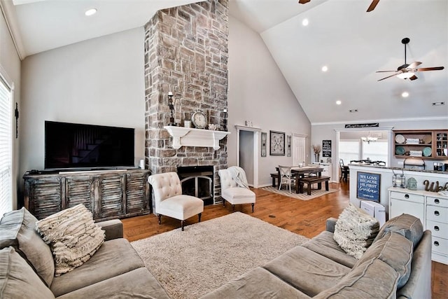 living room featuring ceiling fan, high vaulted ceiling, a fireplace, and hardwood / wood-style floors