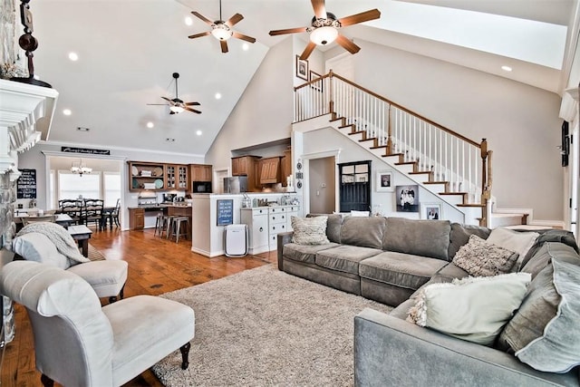 living room featuring ceiling fan with notable chandelier, hardwood / wood-style floors, and high vaulted ceiling