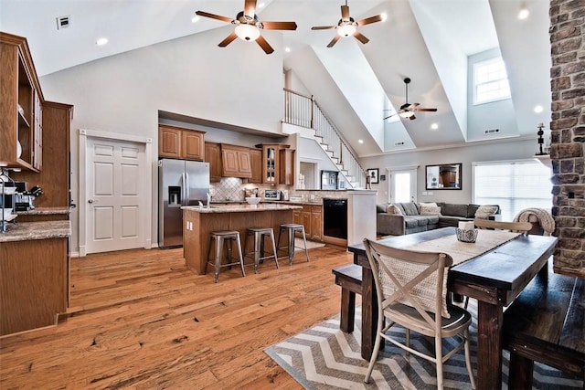 dining room with plenty of natural light, high vaulted ceiling, ceiling fan, and light wood-type flooring