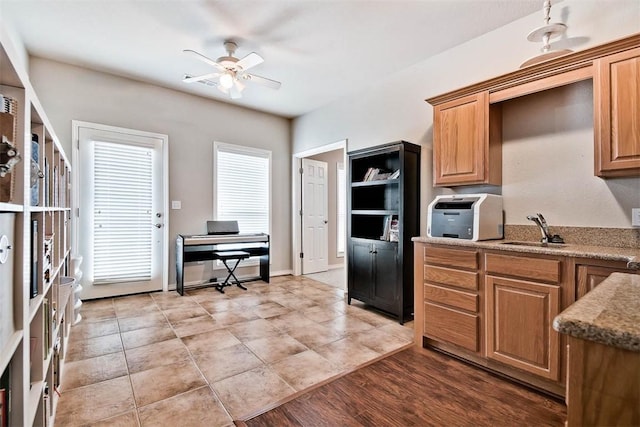 kitchen with light tile patterned flooring, sink, light stone counters, and ceiling fan