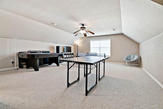 rec room featuring vaulted ceiling, light colored carpet, ceiling fan, and a textured ceiling