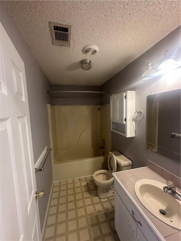 full bathroom with washtub / shower combination, vanity, toilet, and a textured ceiling