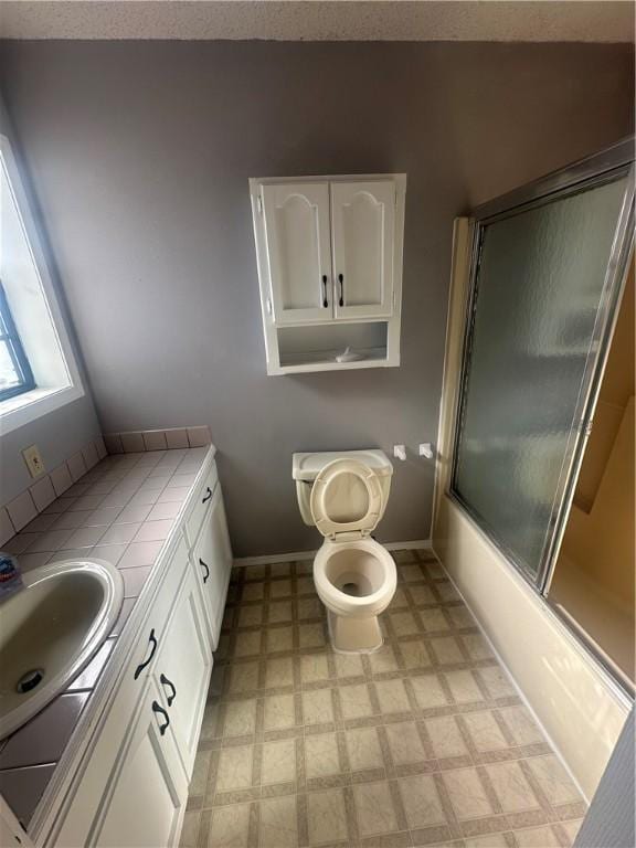 full bathroom with vanity, bath / shower combo with glass door, and toilet