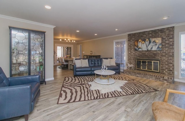 living room with crown molding, a brick fireplace, and light hardwood / wood-style floors