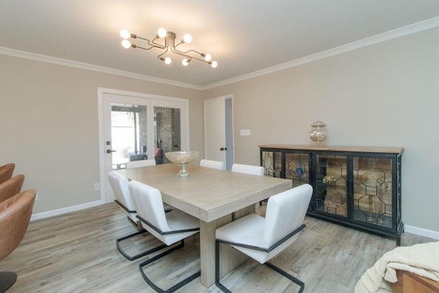 dining space featuring ornamental molding, a chandelier, and light hardwood / wood-style floors