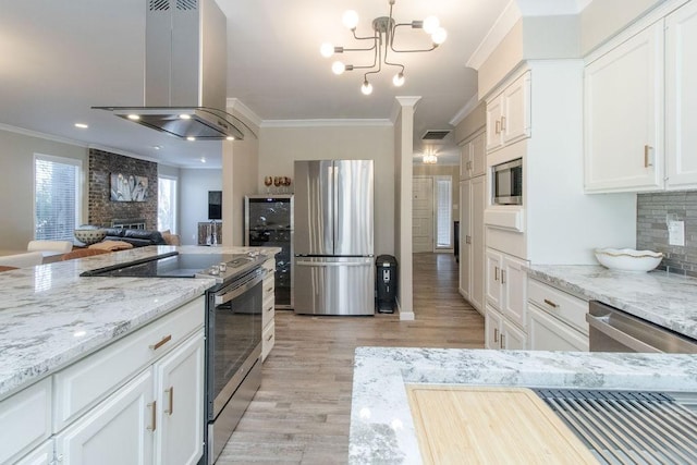 kitchen featuring ornamental molding, appliances with stainless steel finishes, island range hood, and white cabinets