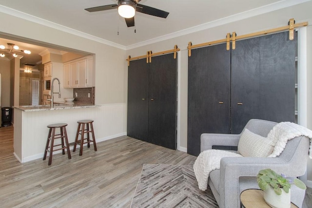 sitting room with crown molding, sink, a barn door, and light hardwood / wood-style floors