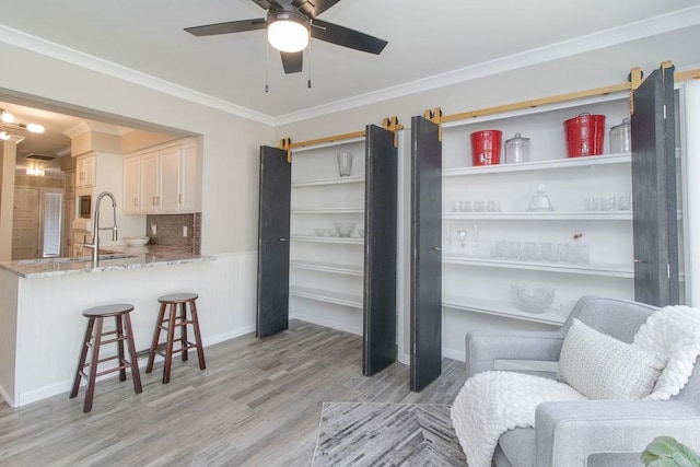 sitting room featuring crown molding, sink, ceiling fan, and light wood-type flooring